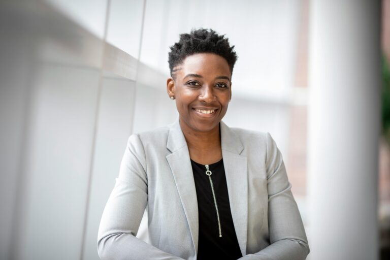 Confident businesswoman smiling in a modern office hallway, showcasing professional attire for corporate portrait photography