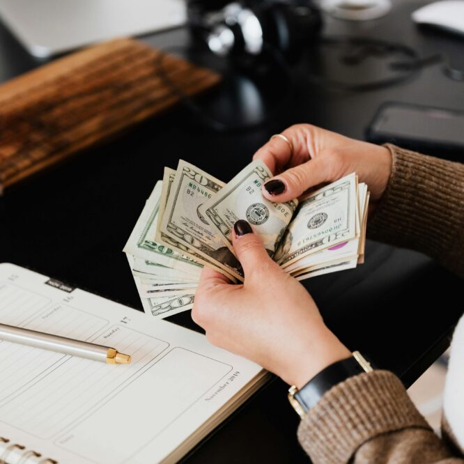 make money with photography in 2025 – person counting cash at a desk with planner and camera gear