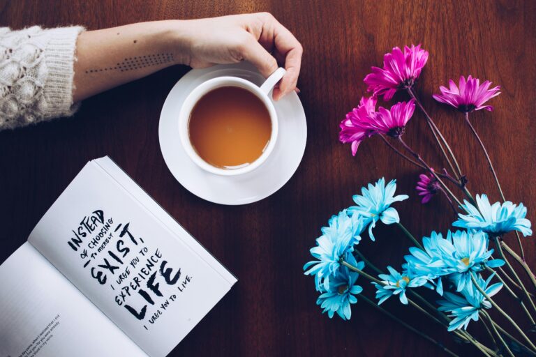 Flat lay photo of a motivational quote, coffee cup, and vibrant blue and purple flowers on a wooden table — creative inspiration for social media and photography blogs