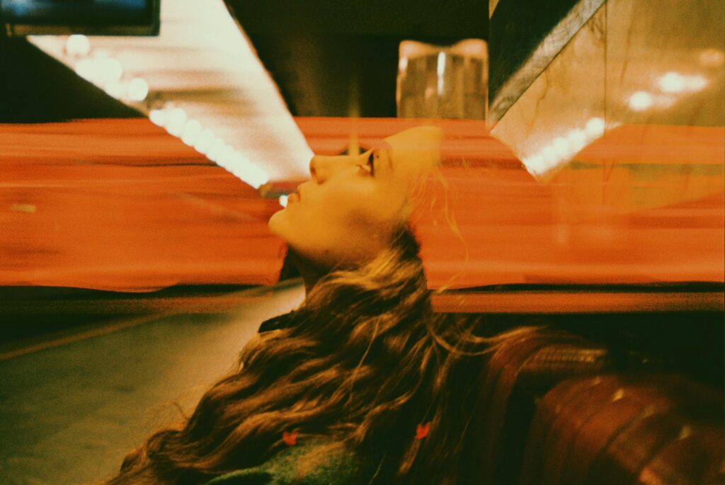 Surreal abstract photograph using double exposure technique—profile of a woman’s face blended with blurred motion of red lights in an urban setting, creating a dreamy and dynamic visual effect.
